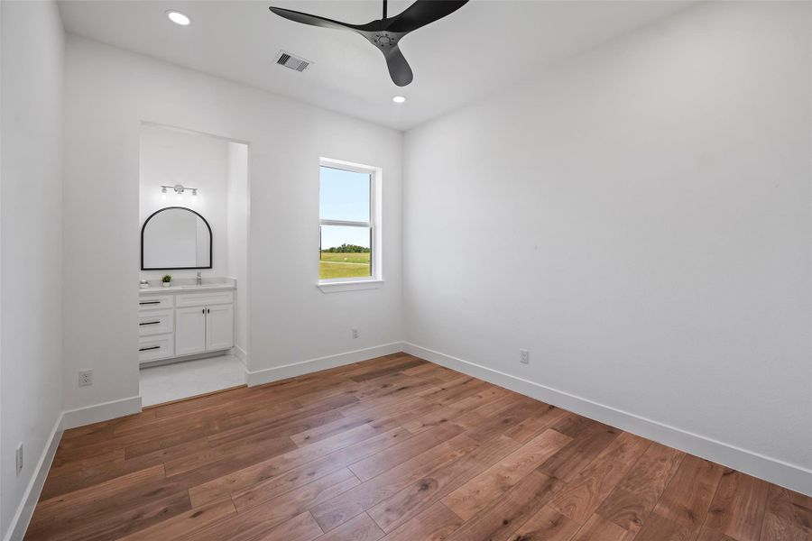 Spacious second bedroom featuring natural light, sleek LVP floors, and an en-suite bathroom.