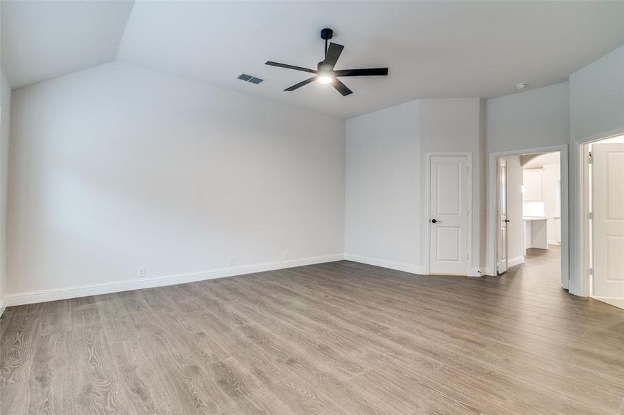 Owners Suite with ensuite, vaulted ceiling, light hardwood / wood-style flooring, and ceiling fan