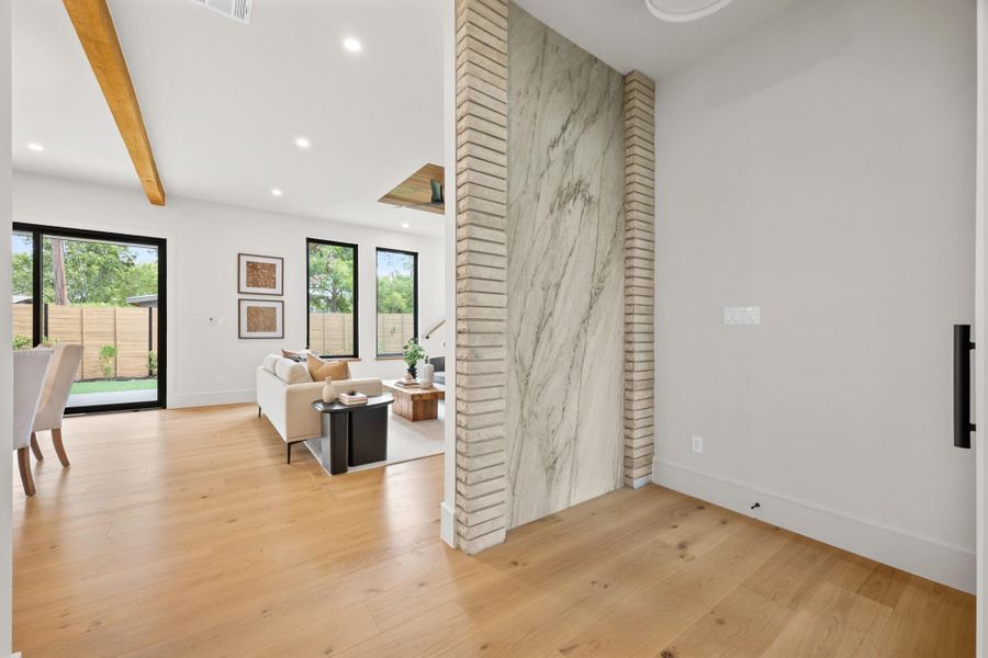 Gleaming hardwood floors and a striking marble accent wall define this welcoming entryway.