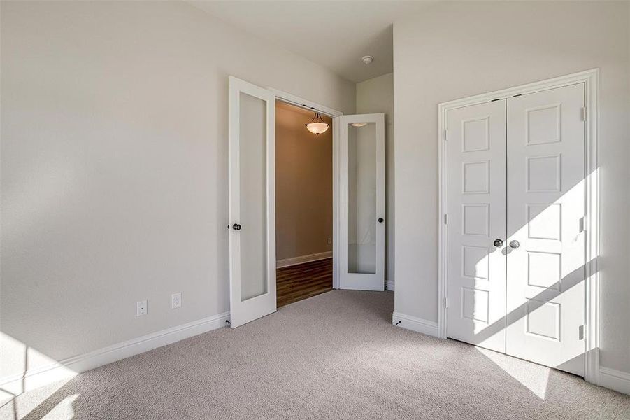 Unfurnished bedroom with light carpet, a closet, and french doors