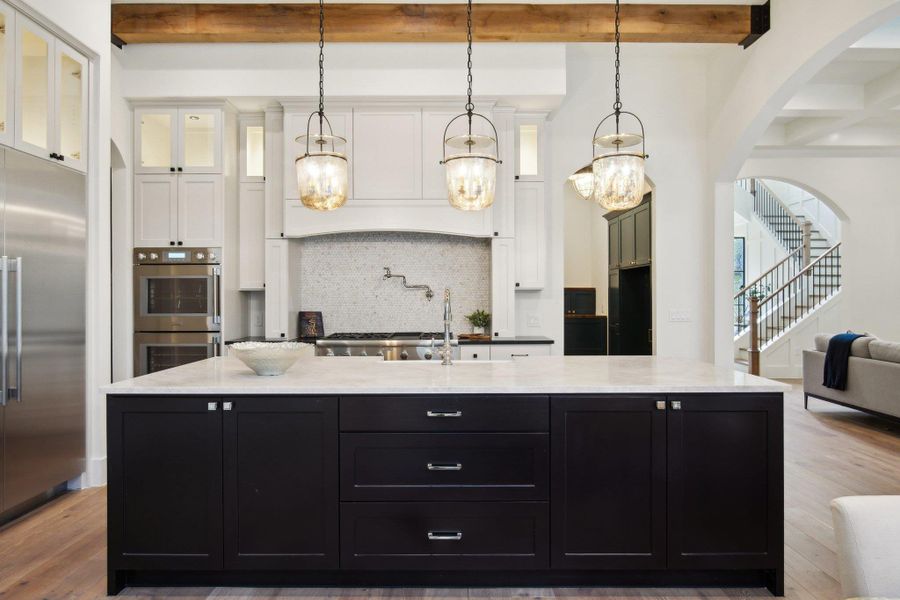 Kitchen featuring beam ceiling, backsplash, dark cabinetry, stainless steel appliances, and white cabinets