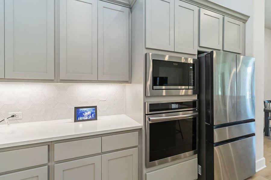 A well-appointed kitchen showcasing contemporary cabinetry, a sleek hexagon tile backsplash, and integrated stainless steel appliances.