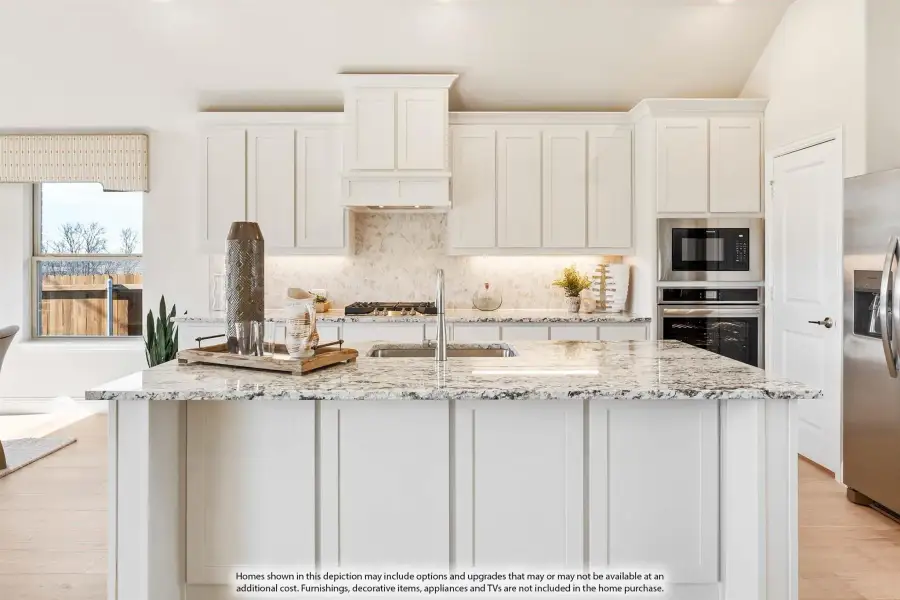 Kitchen with large center island, granite countertops, white cabinets, and stainless steel appliances