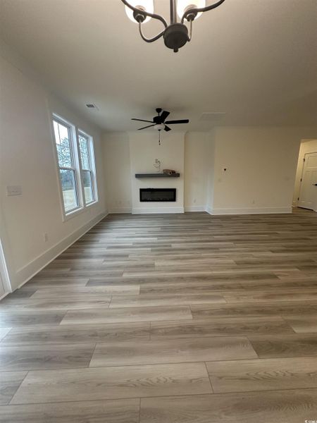 Unfurnished living room with a fireplace, a chandelier, and light wood-style flooring