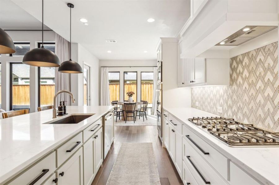 Kitchen featuring dark wood-type flooring, sink, white cabinets, stainless steel appliances, and light stone countertops