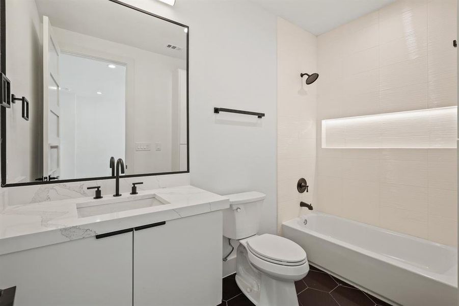 Full bathroom featuring toilet, tiled shower / bath combo, vanity, and tile patterned floors