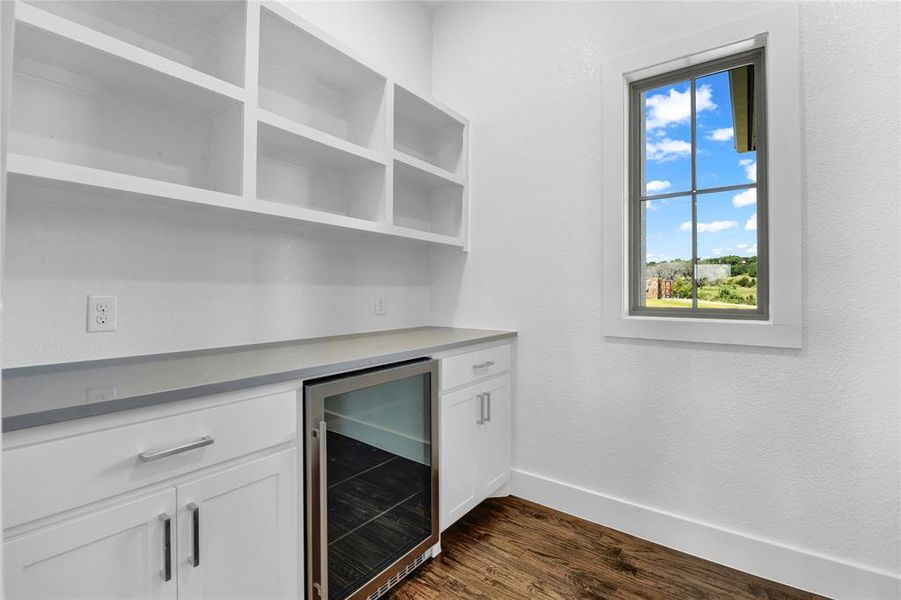 Kitchen featuring hanging light fixtures, dark wood-type flooring, appliances with stainless steel finishes, white cabinets, and backsplash