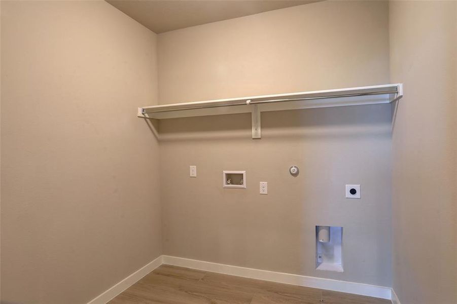 Washroom with gas dryer hookup, light wood-style flooring, hookup for an electric dryer, and hookup for a washing machine Washroom with gas dryer hookup, light wood-style flooring, hookup for an electric dryer, and hookup for a washing machine