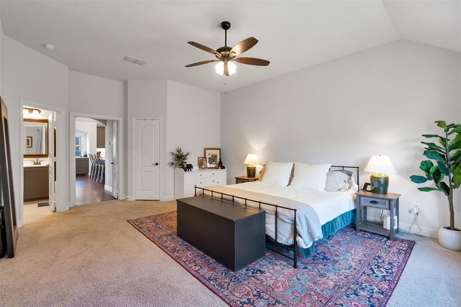 Carpeted bedroom with ceiling fan, ensuite bath, and vaulted ceiling