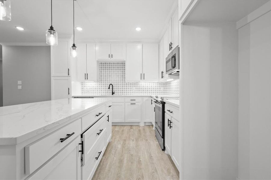 Kitchen featuring decorative light fixtures, light hardwood / wood-style flooring, appliances with stainless steel finishes, decorative backsplash, and white cabinets