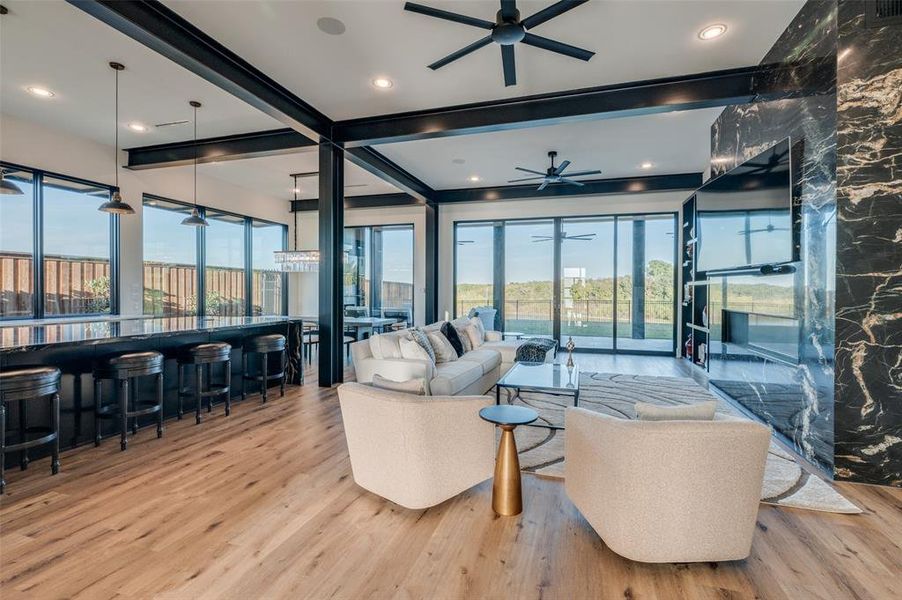 Living room featuring ceiling fan, beam ceiling, plenty of natural light, and light hardwood / wood-style flooring