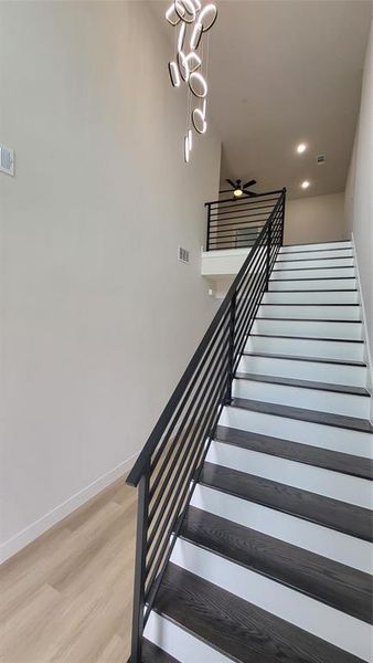 Staircase with a ceiling fan, wood finished floors, baseboards, visible vents, and recessed lighting