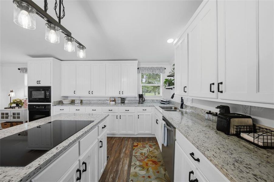 Spacious kitchen featuring white cabinetry, light granite countertops, a built-in oven, and a large center island with an integrated cooktop