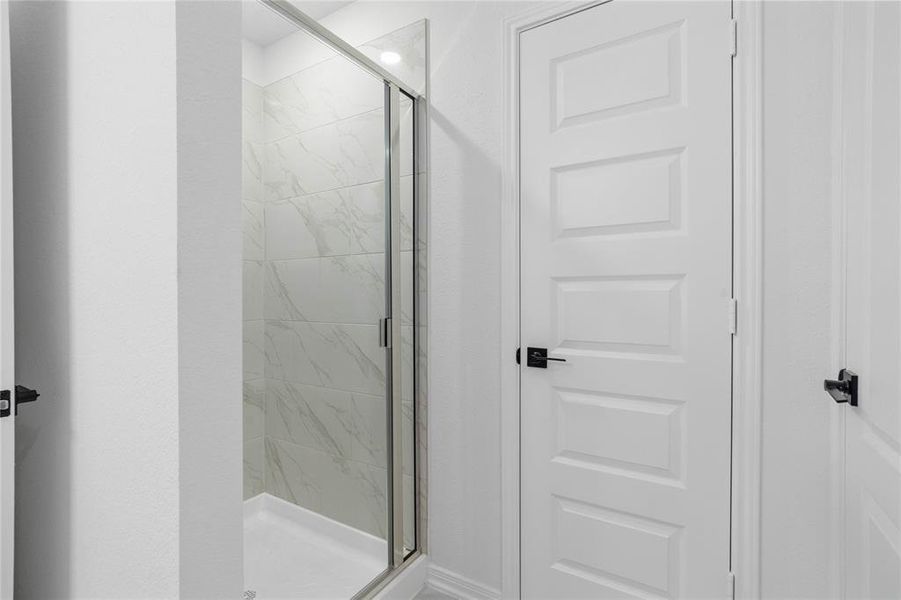 Additional view of the primary bathroom featuring the walk-in shower with tile surround.