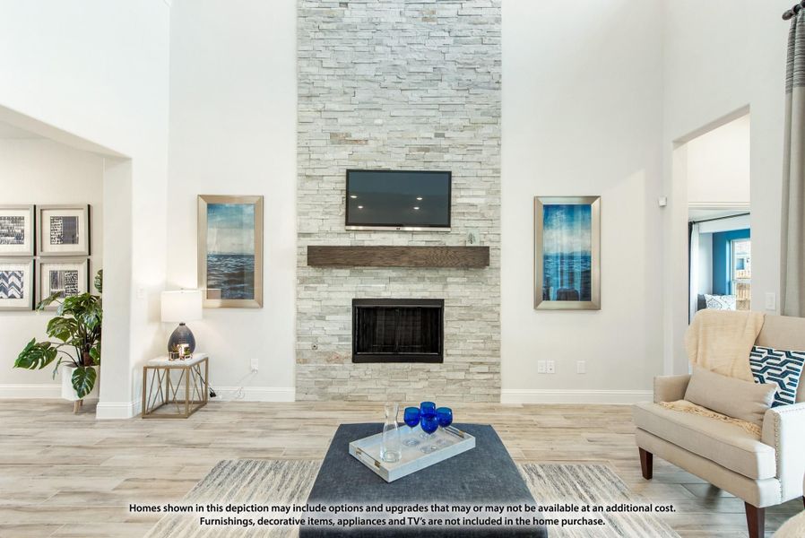 Living room with floor-to-ceiling stacked stone fireplace, wall-mounted TV, wood mantel, and light hardwood floors