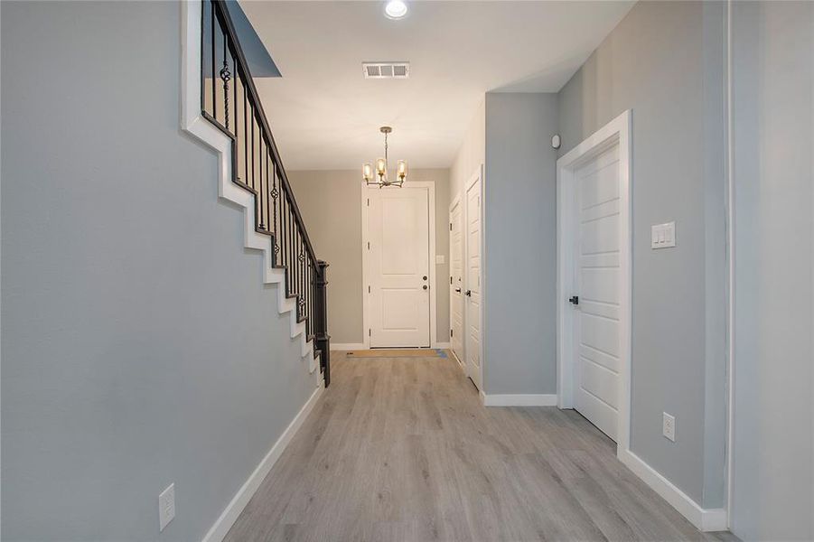 Corridor featuring an inviting chandelier and light hardwood / wood-style floors