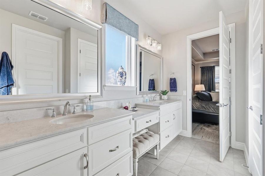 Bathroom featuring double vanity, healthy amount of natural light, ensuite bath, and light tile patterned floors