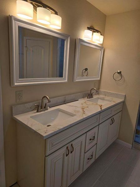 Bathroom featuring double vanity and baseboards Bathroom featuring double vanity and baseboards