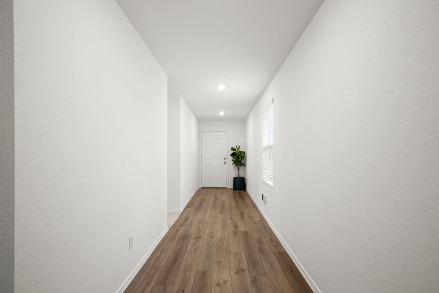 The entry hallway flows past the secondary bedroom hallway into the main living area.