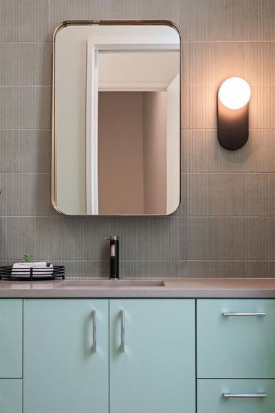 Powder bath featuring custom tile extending to the ceiling, complemented by stylish lighting fixtures and high-end finishes.