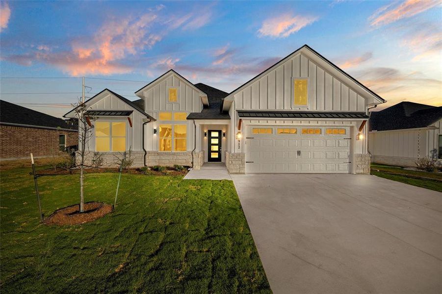 Modern farmhouse with board and batten siding, a standing seam roof, a metal roof, and driveway