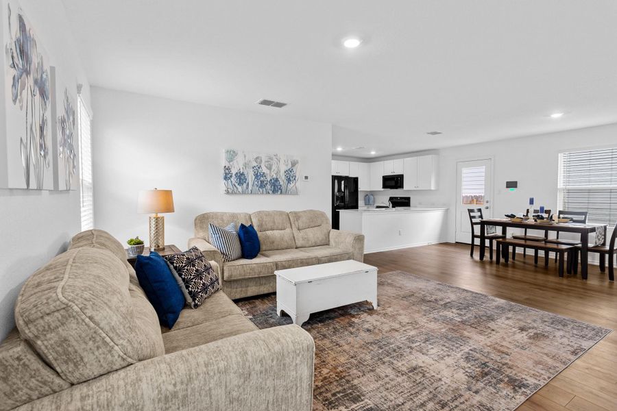 Open-concept living area with wood-finish flooring, white walls, and recessed lighting
