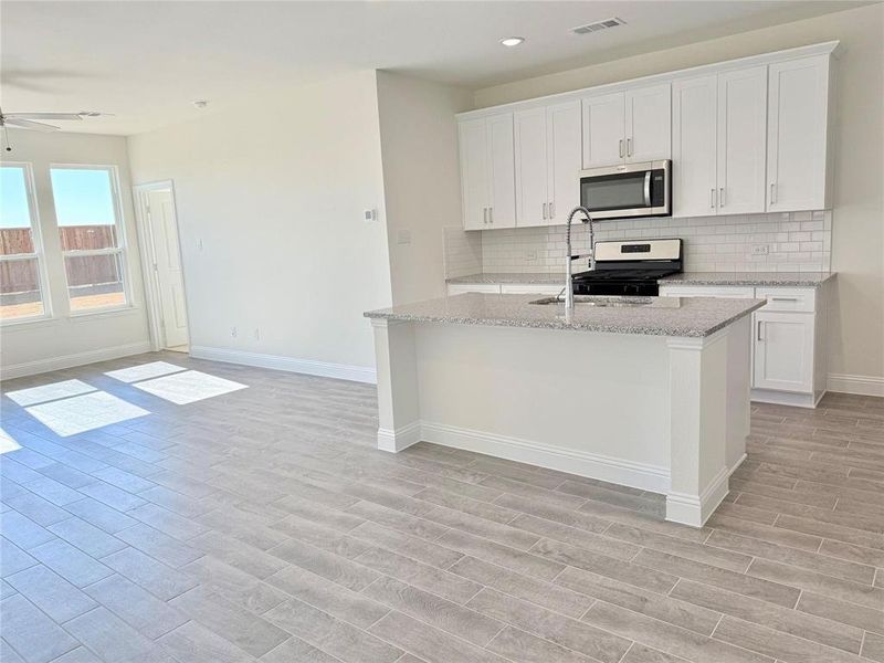 Kitchen featuring a center island with sink, visible vents, appliances with stainless steel finishes, light wood-style floors, and open floor plan