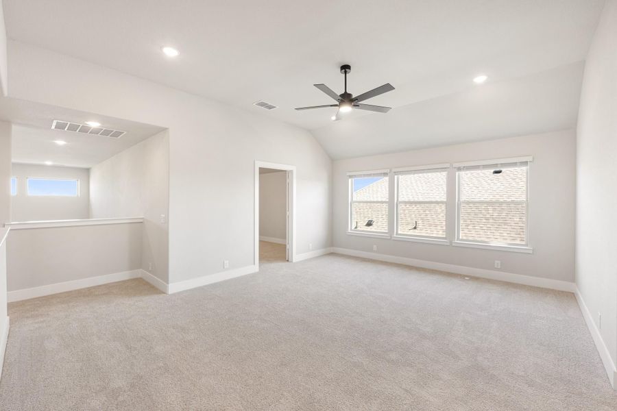 Spacious empty bedroom with vaulted ceiling, ceiling fan, carpet flooring, and large windows Spacious empty bedroom with vaulted ceiling, ceiling fan, carpet flooring, and large windows