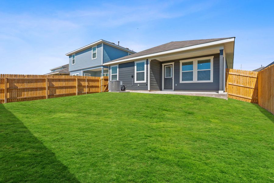 Rear view of house with a fenced backyard and a patio