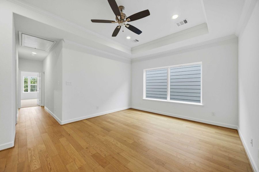 Let the fun begin in this vibrant game room, with a tray ceiling, ceiling fan, and a wall of windows flooding the space with light.