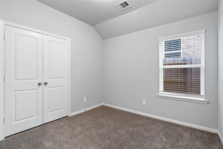 Perfect for guests or a quiet home office, this room features soft plush carpeting, a window with fitted blinds, sloped ceiling, and ample sized closet space.