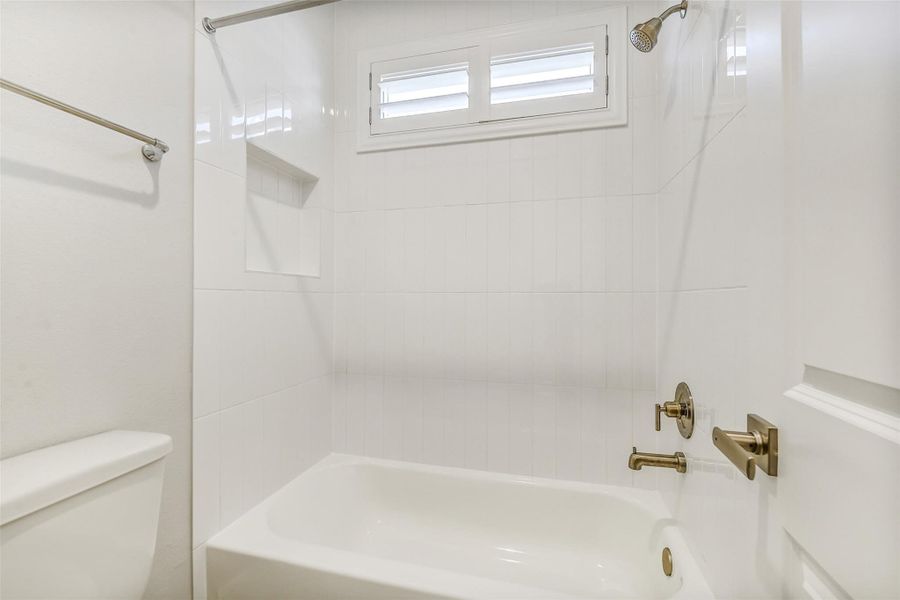 The bath has tile surround and an inset in the wall to hold the soap and shampoo. Notice the Sunburst shutters on the windows. The bath has tile surround and an inset in the wall to hold the soap and shampoo. Notice the Sunburst shutters on the windows.