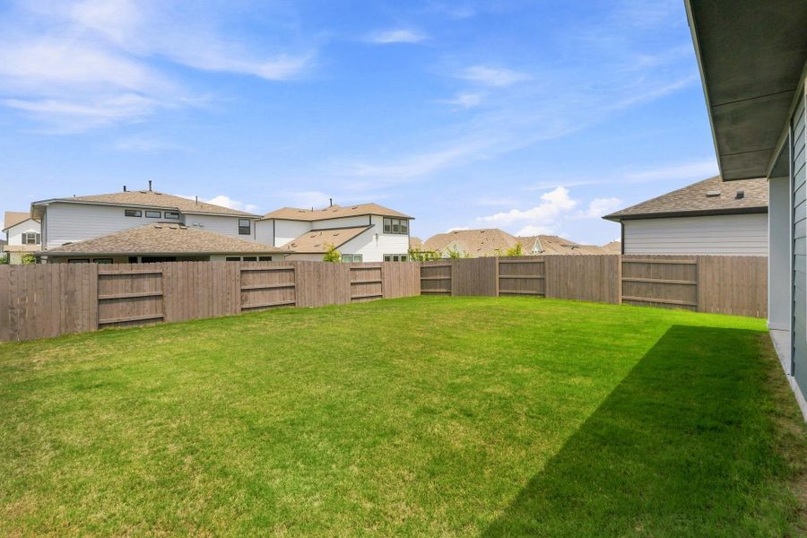 Wide-angle view of the deep green lawn and private wood privacy fence with ample room for outdoor play or a garden layout. Wide-angle view of the deep green lawn and private wood privacy fence with ample room for outdoor play or a garden layout.