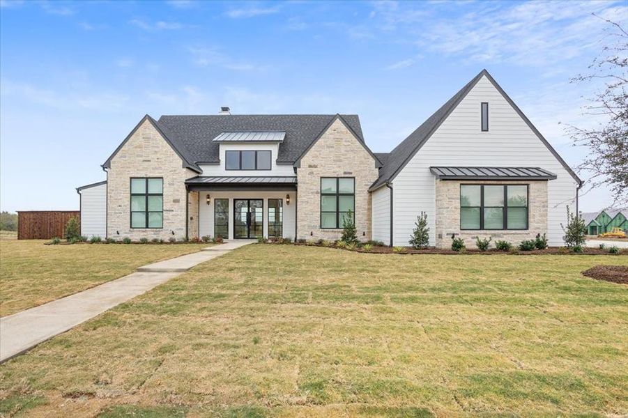 Modern farmhouse style home with a standing seam roof, stone siding, and a metal roof