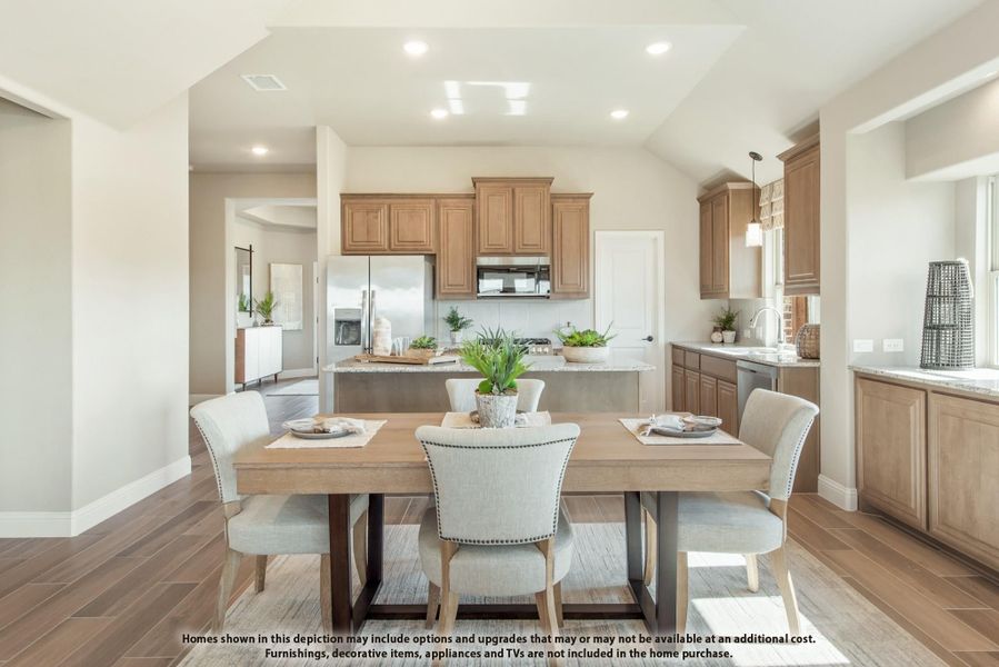 Open dining area with wood table and upholstered chairs adjoining kitchen with tan cabinets and center island