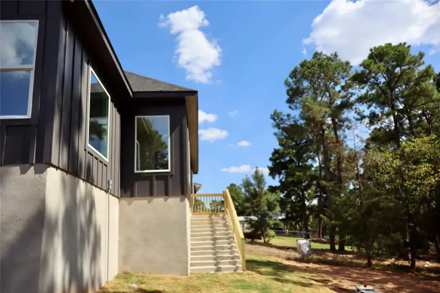 View of side of home featuring stairway, board and batten siding, and a lawn