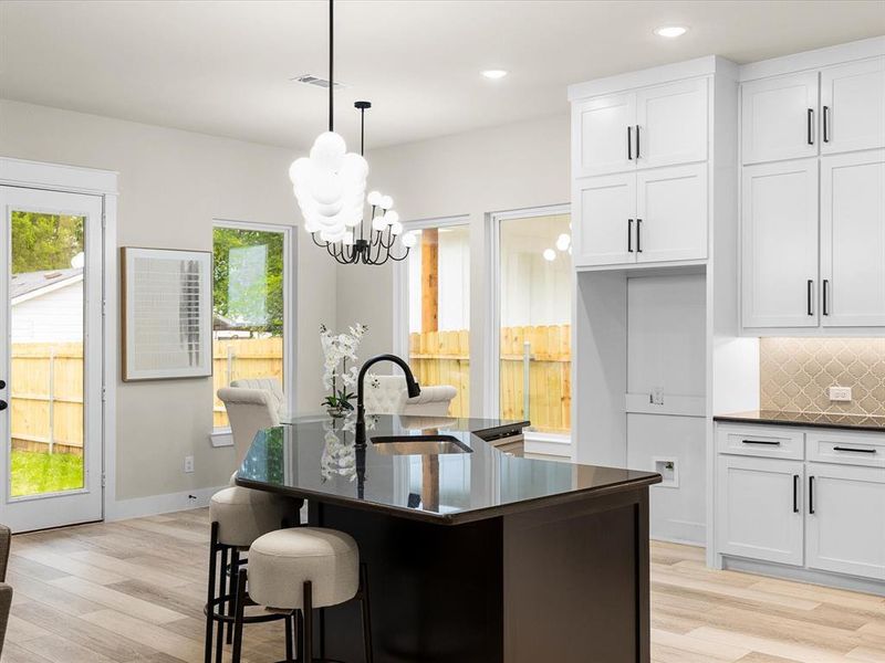 Kitchen featuring dark countertops, backsplash, light wood finished floors, a chandelier, and recessed lighting