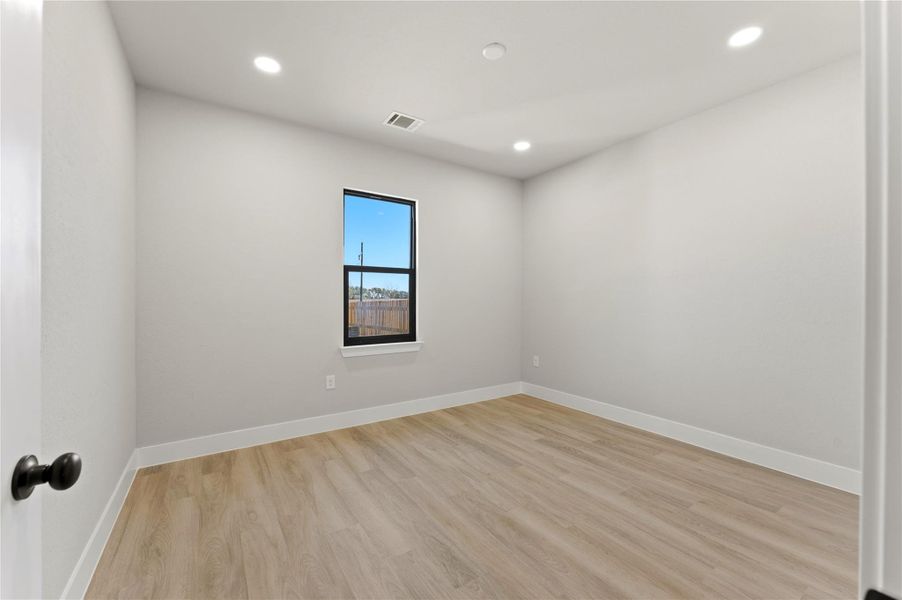 Empty room with light wood finished floors and recessed lighting
