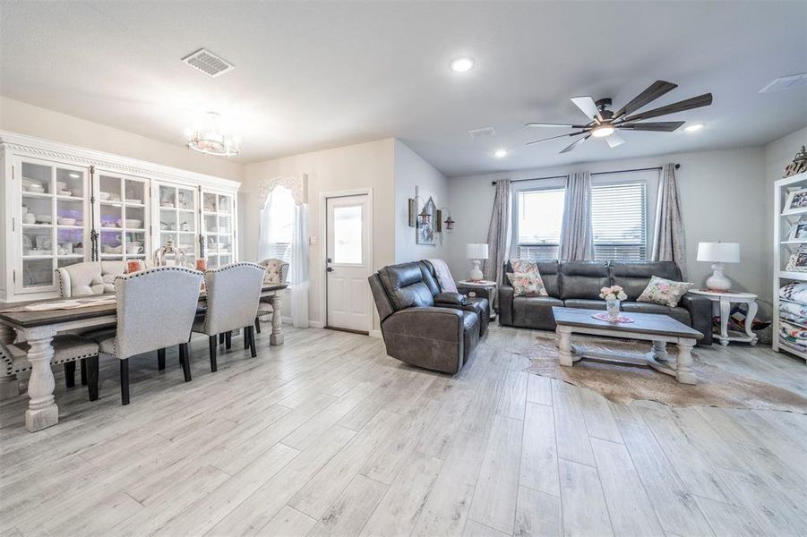 Living room featuring ceiling fan with notable chandelier and light hardwood / wood-style flooring