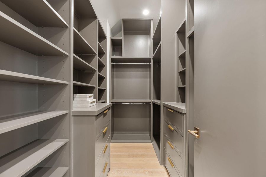 The walk in closet boasts custom-built cabinetry with ample storage and brass pulls. The walk in closet boasts custom-built cabinetry with ample storage and brass pulls.