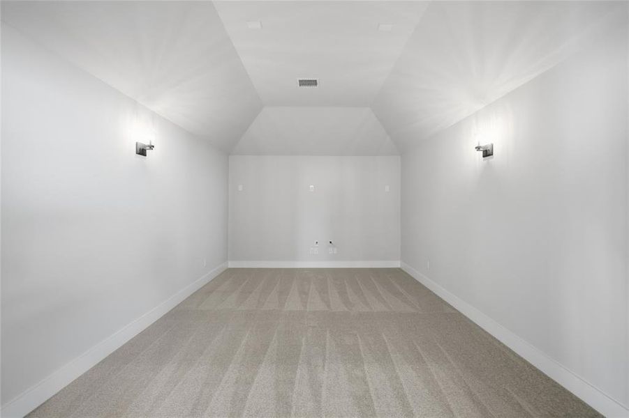 Additional living space featuring light colored carpet and vaulted ceiling