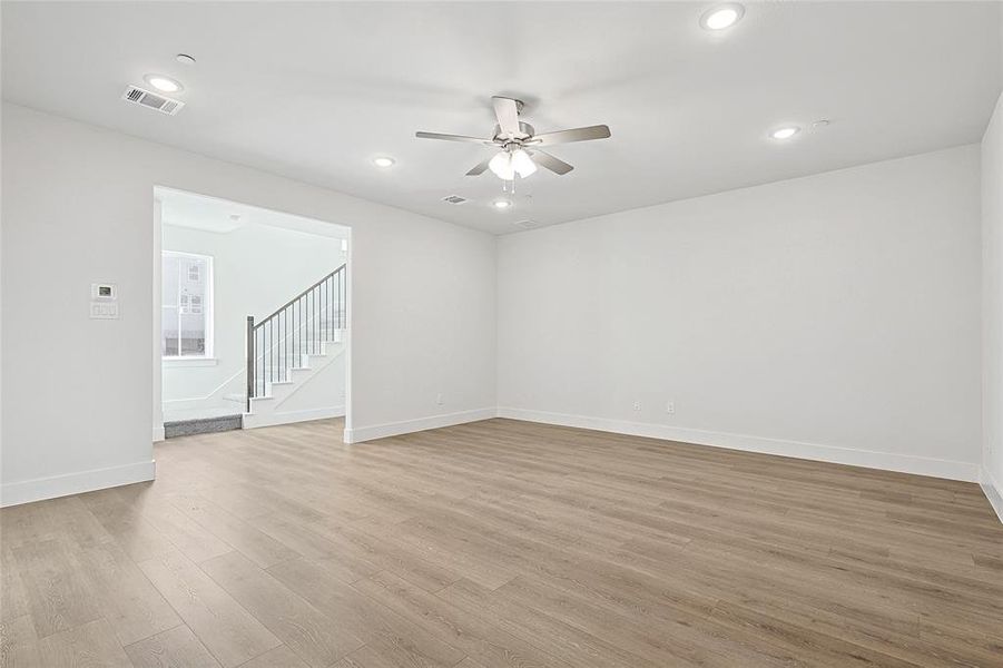 Spacious open-concept living area featuring light-toned flooring, recessed lighting, and a ceiling fan