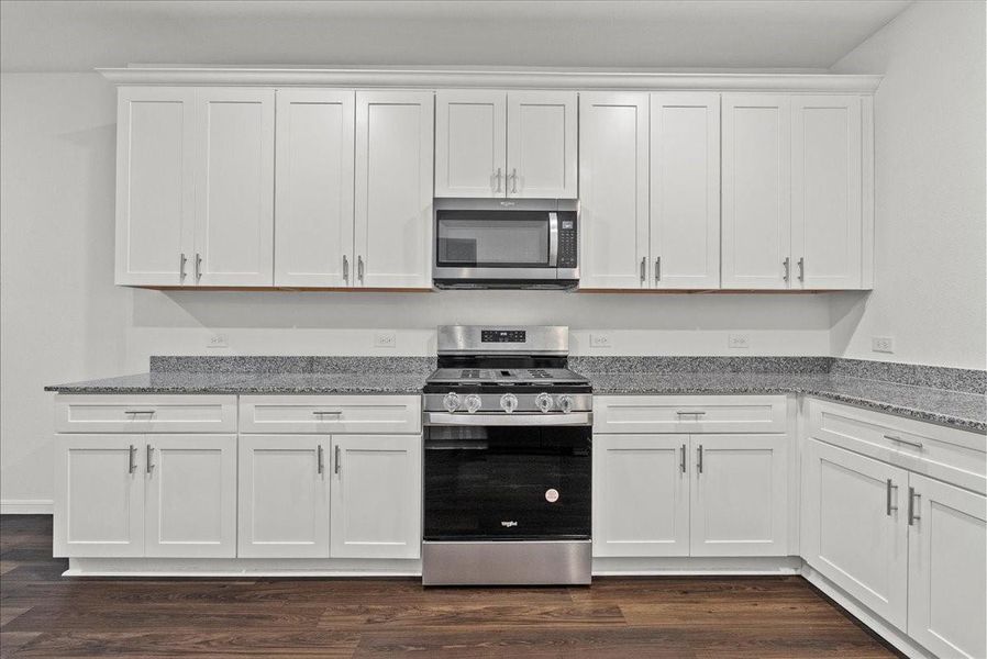 Another view of the Kitchen showing so many cabinets, the oven, cooktop, and microwave