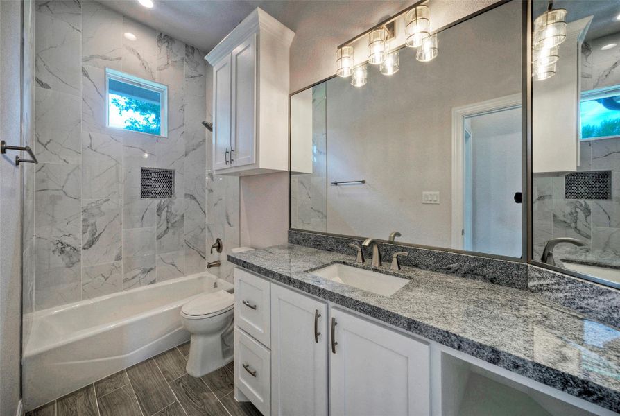 Bathroom featuring vanity, washtub / shower combination, and wood finish floors Bathroom featuring vanity, washtub / shower combination, and wood finish floors