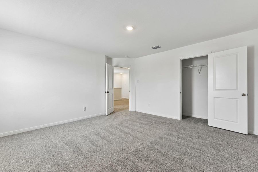 Neutral gray carpeted room with white walls, a single recessed ceiling light, and a built-in closet with a hanging rod