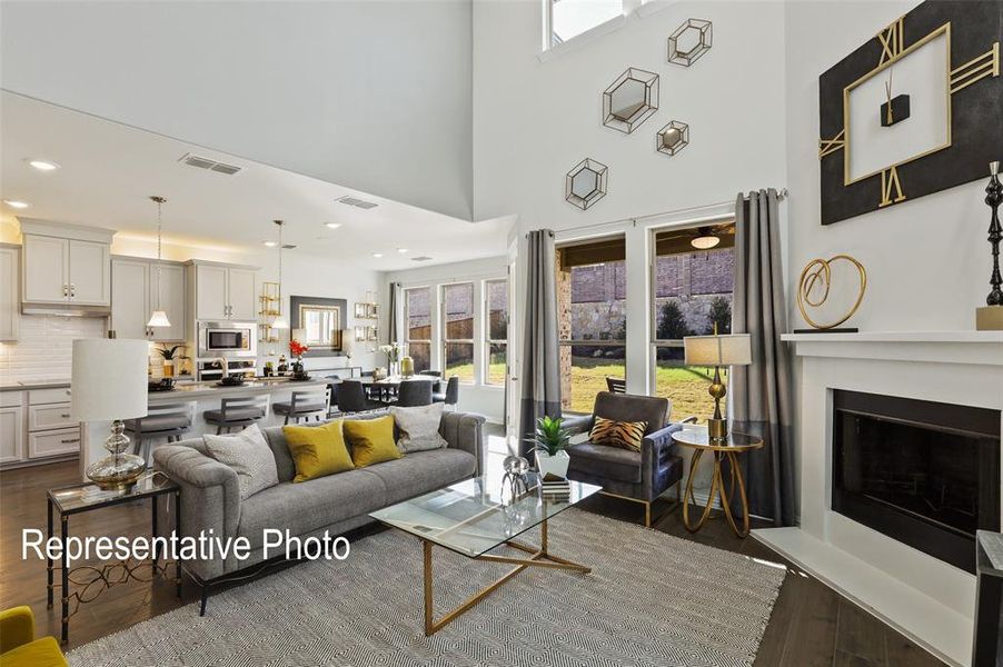 Spacious open-concept living area featuring a vaulted ceiling, fireplace with mantel, and large windows