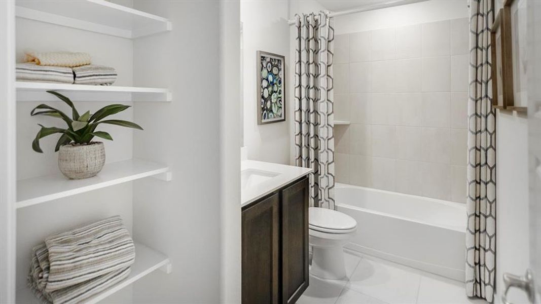 Full bathroom featuring a dark wood-finish vanity with an integrated sink, a white bathtub with subway tile surround, and a built-in shower niche