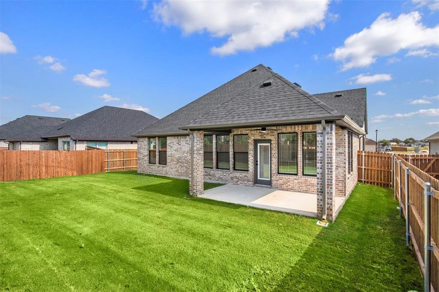 Back of property featuring brick siding, roof with shingles, a patio area, and a fenced backyard