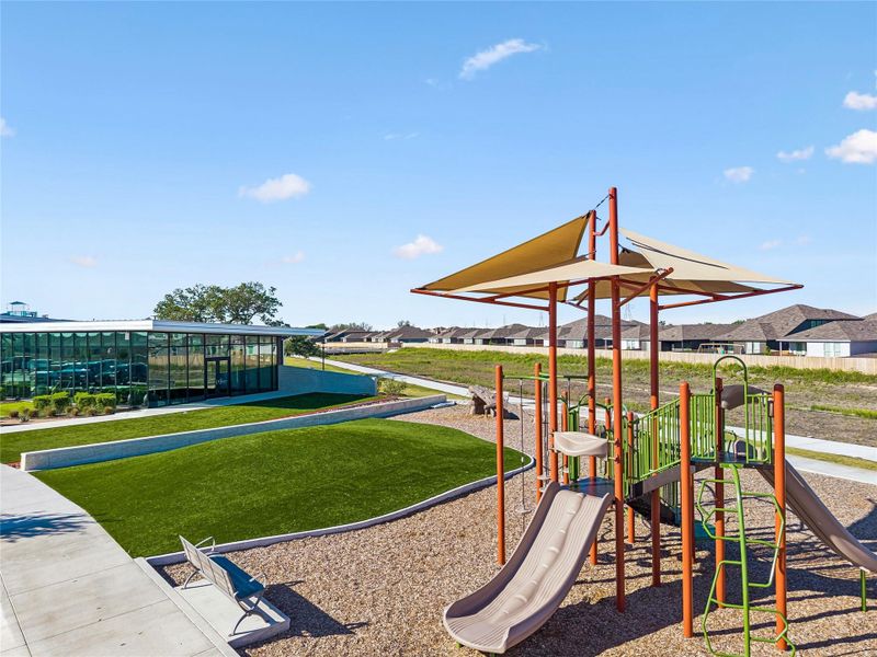 Community playground featuring multiple slides, climbing elements, and a shade canopy Community playground featuring multiple slides, climbing elements, and a shade canopy