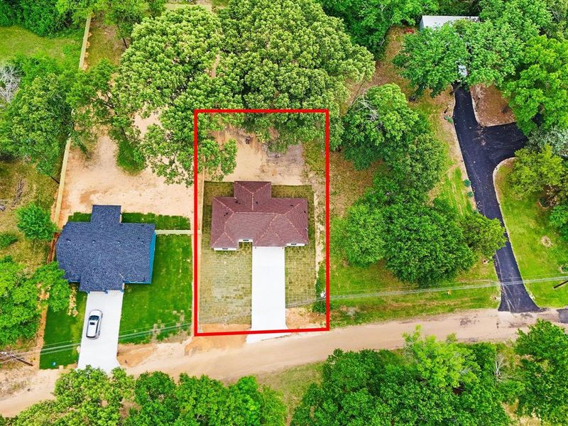 Aerial perspective highlighting a property with a distinct brown-shingled roof and a light-colored driveway Aerial perspective highlighting a property with a distinct brown-shingled roof and a light-colored driveway